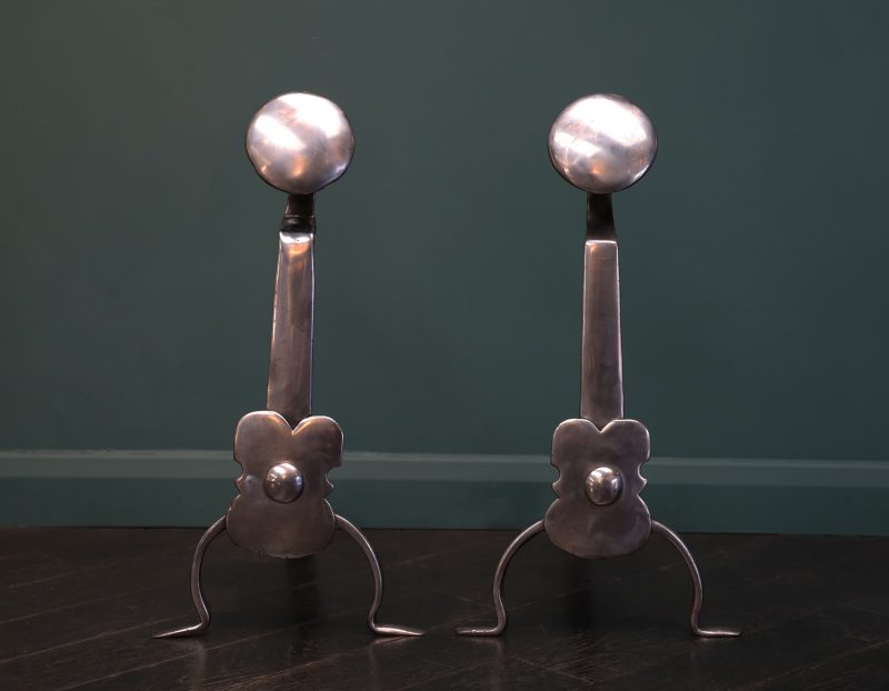 A Pair of English Polished Wrought Fire Dogs with Shield