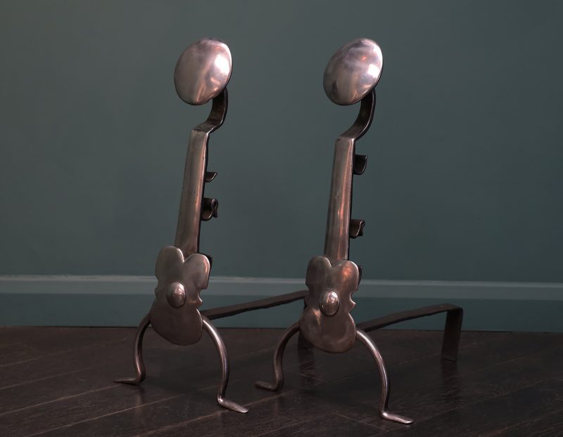 A Pair of English Polished Wrought Fire Dogs with Shield